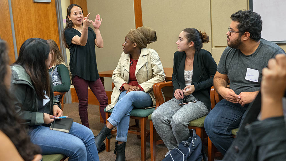 Students sitting in circle with instructor standing and gesturing