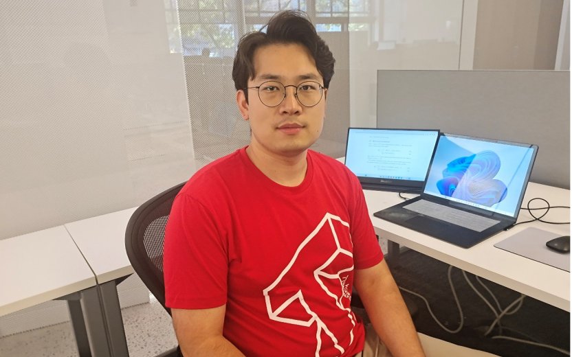Student wearing a T-shirt with a Cornell Tech logo sits in front of a laptop.
