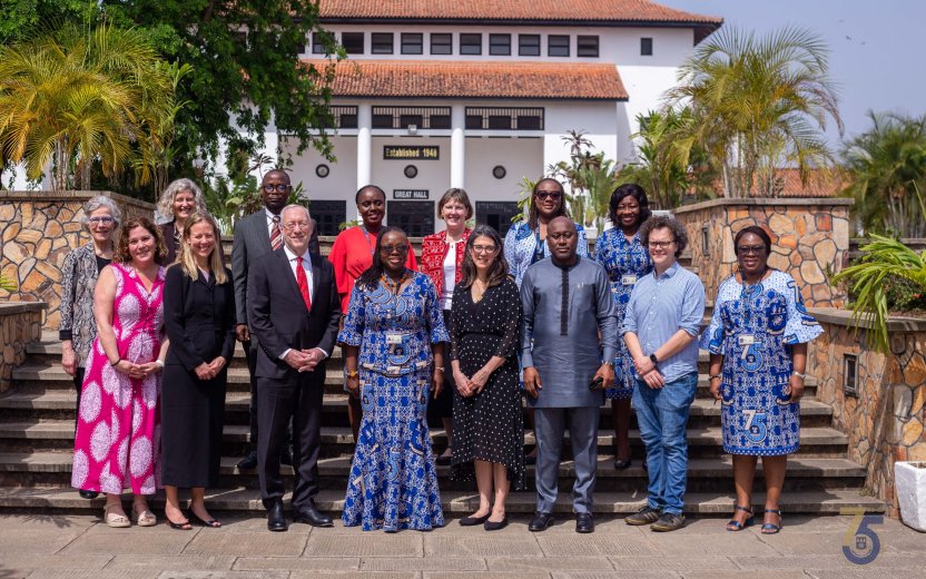 Group stands in front of a building at the University of Ghana. 