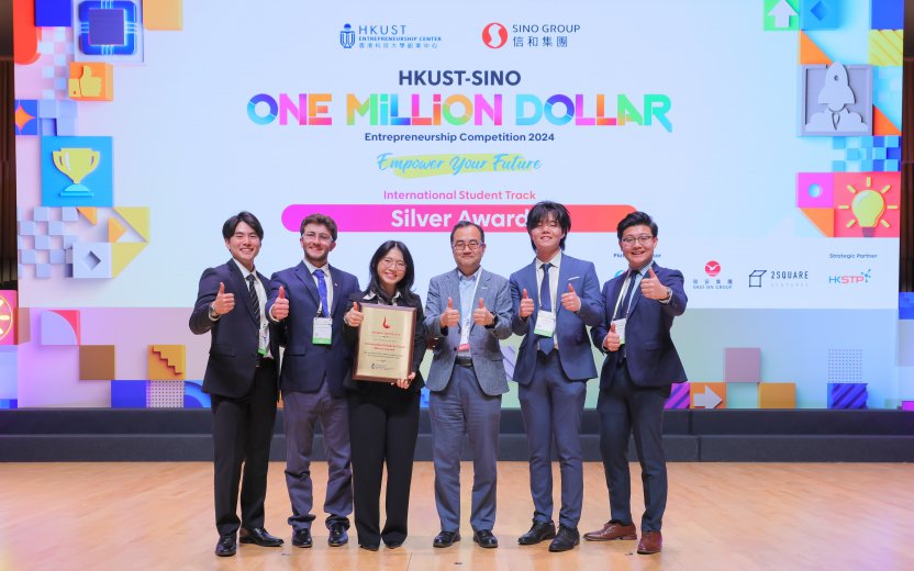 Five students and their host stand in front of a screen announcing their silver award. 