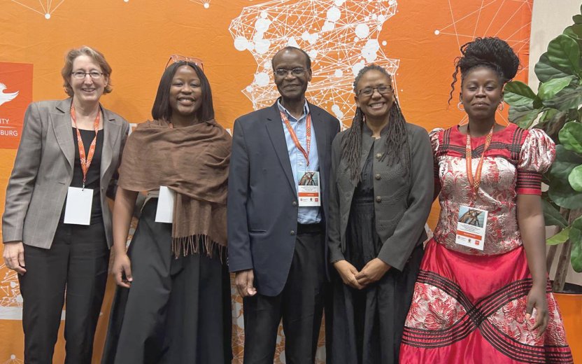 five conference attendees standing in front of a banner.