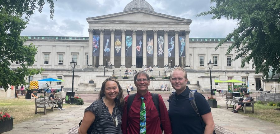 Three people standing in front of a building with columns.