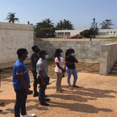 Six students with a faculty member in front of a stone frieze.