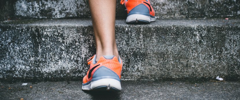 A person's running shoes going up a stone staircase.