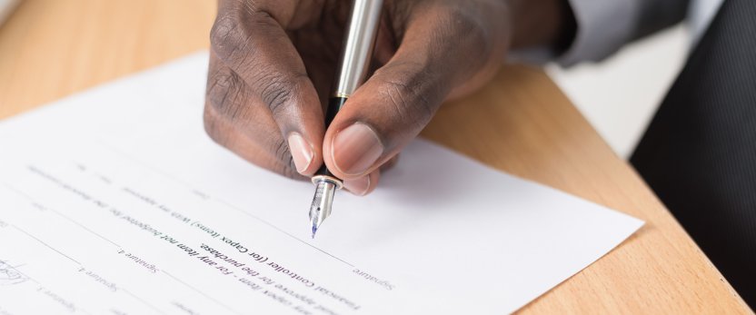 Hand holding a pen and signing a contract. 