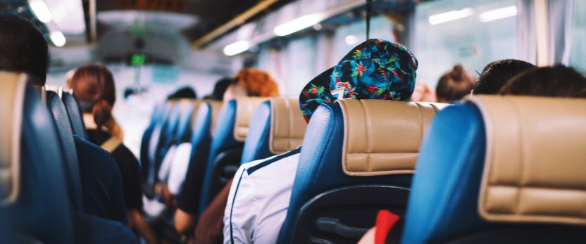 Passengers seen from behind, seated on a charter bus.
