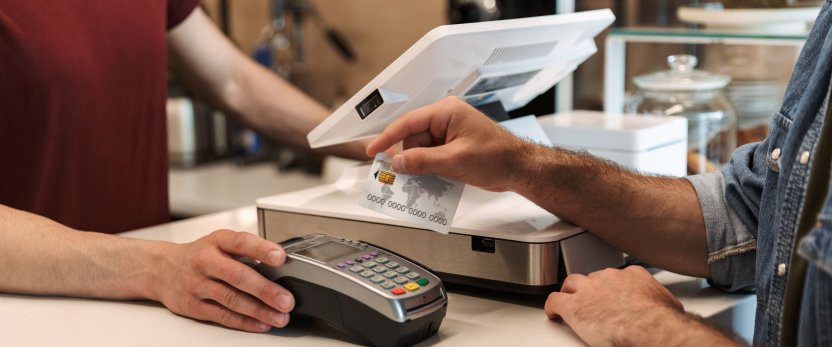 Man paying with a credit card while cashier holds payment terminal.