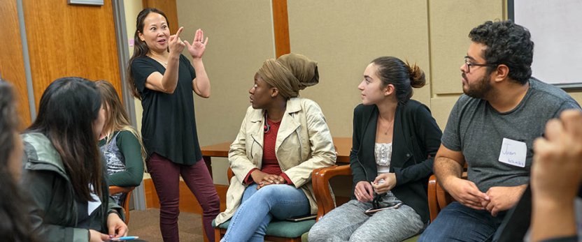 Students sitting in circle with instructor standing and gesturing