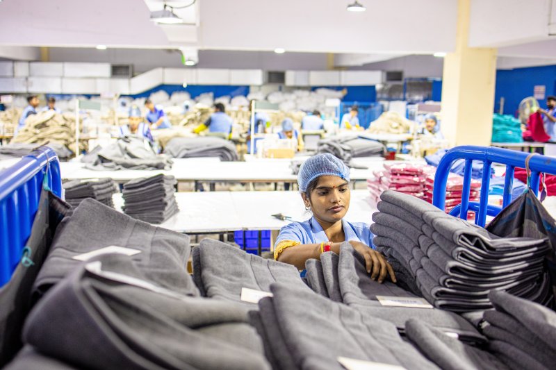 Worker with headcovering in a textile factory stacking towels on a cart