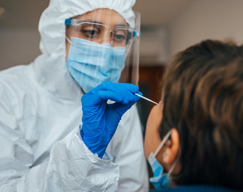 Close up of a health care professional in PPE nasal swabbing a patient