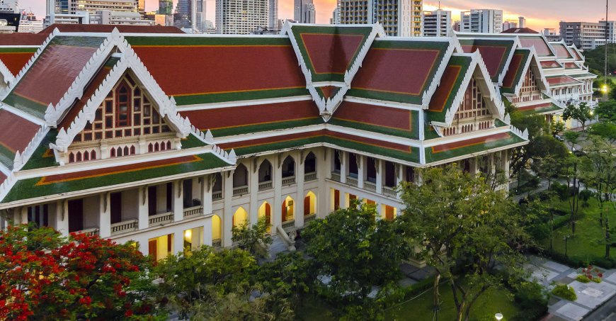 Exterior of Chula's red-roofed auditorium surrounded by trees. 