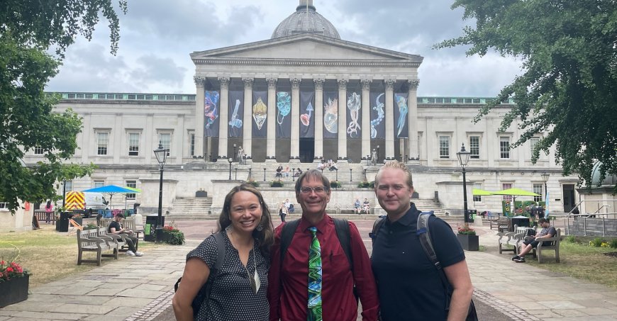 Three people standing in front of a building with columns.