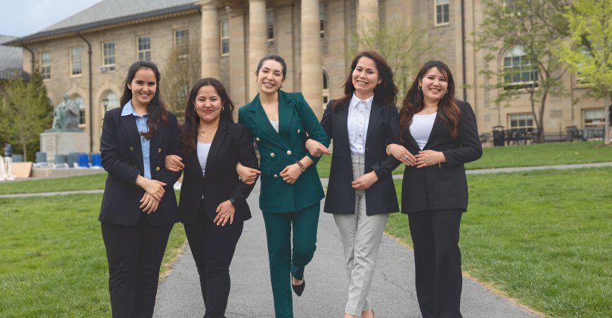 Five graduating Afghan students link arms and walk together on campus.
