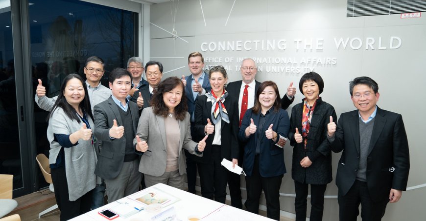 A group of smiling people standing around a conference table. 