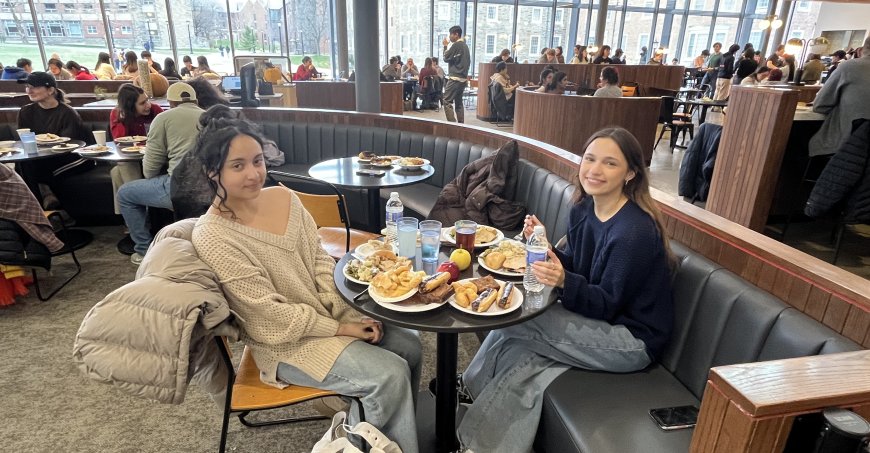 Two students sitting a table at Toni Morrison dining Hall with a table full of plates. 