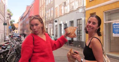 Rebecca Herzberg holds coffee and a pastry with a friend in Copenhagen.