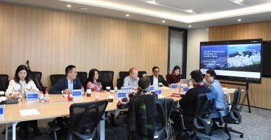 Group sitting around a conference table with a slideshow on a large screen.