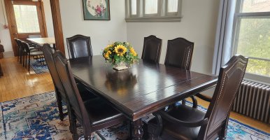 Dark wood dining room table with flower in the center. 