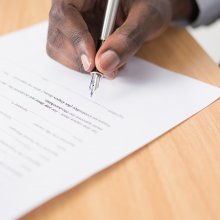 Hand holding a pen and signing a contract.