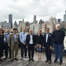 A group of people posing in front of the NYC skyline as seen from Roosevelt Island.