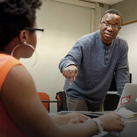 Faculty member standing at table with two seated students