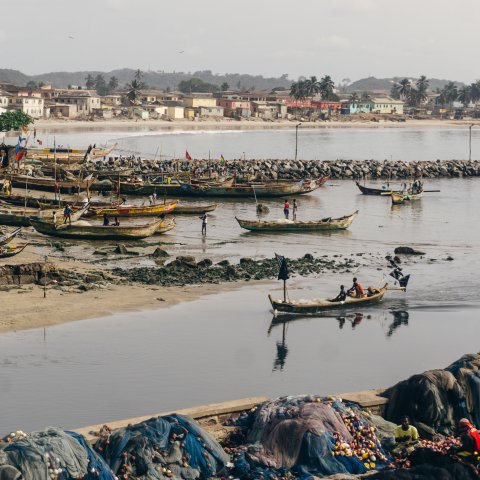 Long boats float across shallow water on the coast of Angola.